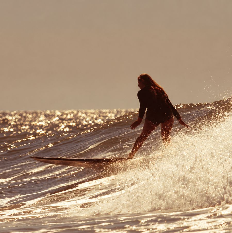 Surfista tomando una ola con luz de atardecer